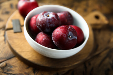 Fresh ripe plums in a white bowl