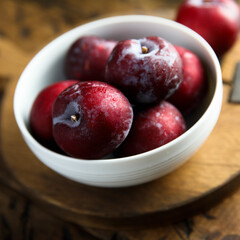 Fresh ripe plums in a white bowl