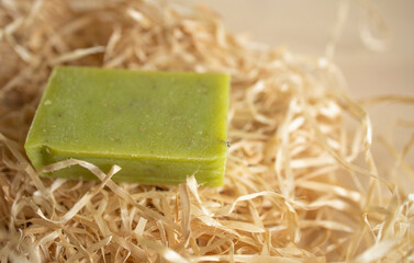 a piece of green soap lies on wrapping paper, on a wooden table surface. Hygiene, soap production, supply disruption, shortages.production of soap, hygiene products