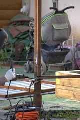 A man is welding a steel gate in the yard of his house