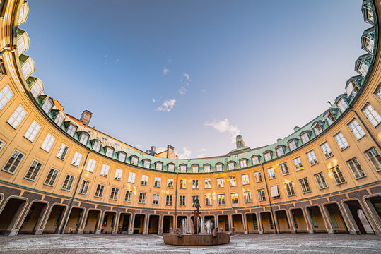 Neat crescent, round shaped building wrapping a small cobbled square. Fine, elegant architecture with a circular arched structure surrounding a tiny stately plaza. Well off or rich neighbours concept