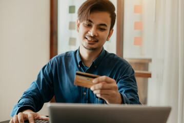 Young smiling male shopping online at home in the morning.