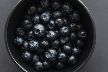 Close up view of organic blueberries in bowl on black background.