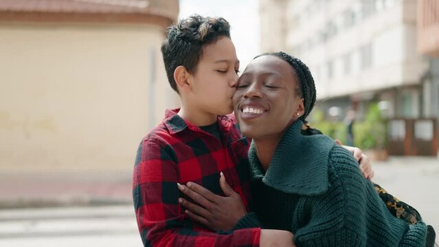 African american mother and son smiling confident hugging each other and kissing at street