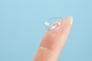 Contact lens on female finger on a blue background, close up. Medicine and vision concept. Woman...