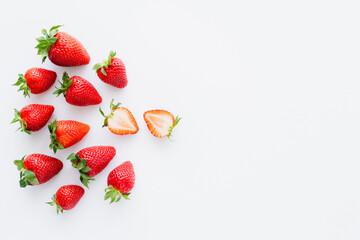 Top view of cut and whole strawberries on white background.