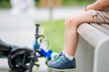 Blond child, cute boy with wounded knee from a fall