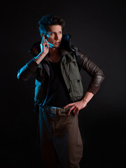 A cyberpunk character talks to someone over an ear implant. Futuristic concept, stylish guy on a black background in neon blue backlight