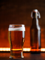 pint glass of light beer on a wooden background. Bottle with a bugle stopper