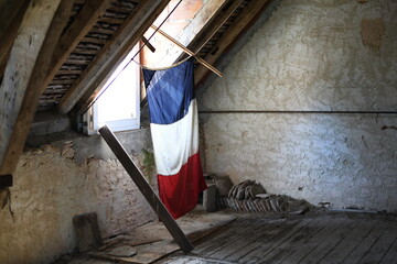 Flag of France bathed in light suspended in an old attic house..