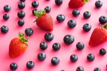 Fototapeta na wymiar Close up view of juicy strawberries and blueberries on pink background.