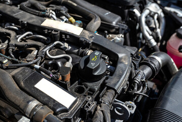 Fototapeta na wymiar Engine compartment in a diesel car, visible closed oil filler in black and engine parts.