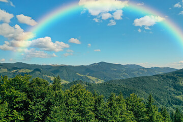 Picturesque mountain landscape and beautiful rainbow in blue sky