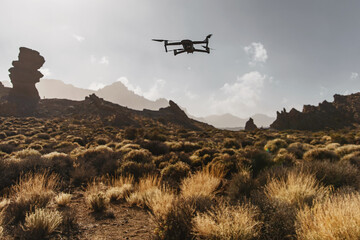 Folding small drone is flying over the mountains.