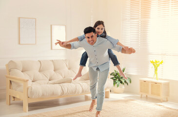 Father and daughter having fun near sofa in living room