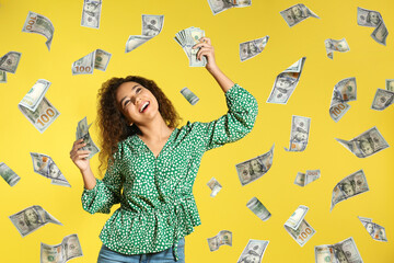 Happy young African American woman with money and falling American dollars on yellow background