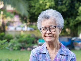 Portrait of a senior woman with short gray hair looking at the camera with a smile while standing garden