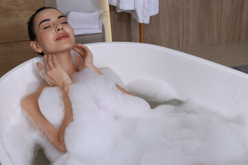 Woman taking bath with shower gel indoors