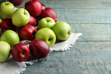 Fresh ripe red and green apples on light blue wooden table, space for text