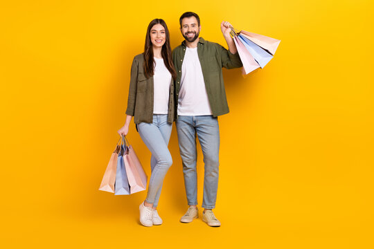 Full body photo of lovely couple hold shopping bags with stylish clothes isolated on yellow color background