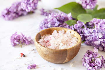 Spa setting. Organic spa sea salt and lilac flowers on a marble.