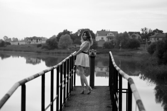 Beautiful slender woman in dress standing on a bridge in black and white
