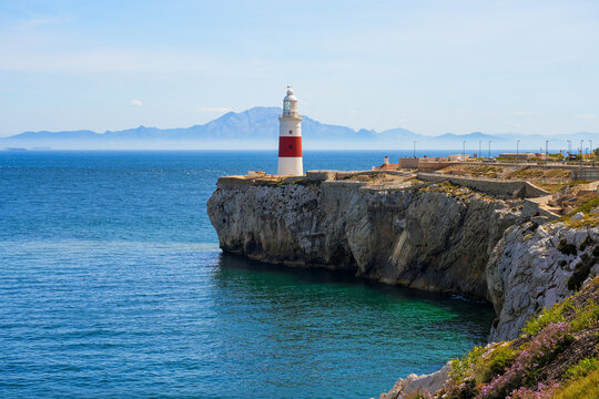 Europa Point Lighthouse facing the strait of Gibraltar on top of sea cliffs with the mountains of Morocco on the distance