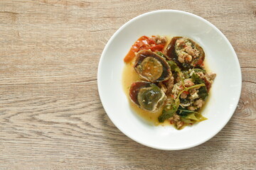 slice boiled  black preserved egg dressing spicy fried chop pork and basil leaf on plate