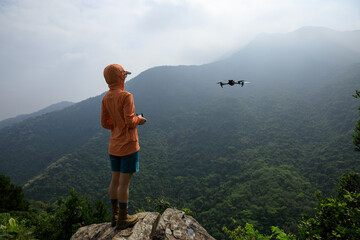 Woman remotel control a flying drone in spring forest