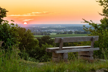Naklejka na ściany i meble A beautiful sunset late Spring over the rolling hills from south Limburg. The wooden bench is an idyllic place for couples to enjoy a romantic evening overlooking to landscape.