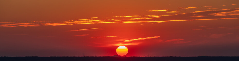 An amazing African sunset over the rolling hills of south Limburg, with the sun as a yellow ball of...