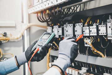 Electrical engineer using digital multi-meter measuring equipment to checking electric current...