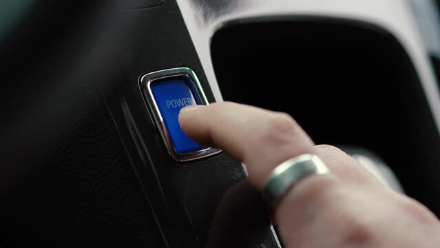 Start keyless ignition hybrid car electric engine. Finger pushing Blue Power Button, close up. Modern technologies in the car