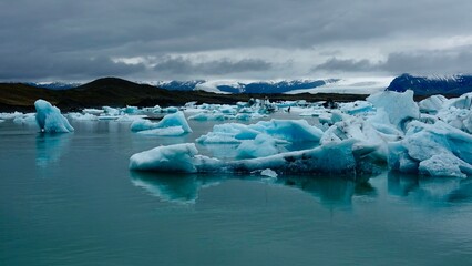 Gletscher Fjord und Gletscher Lagune. Kleine Eisstücke und riesige Eisberge - alles mit bewölktem Himmel.