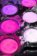 Red, purple, violet and pink colors on the dirty artist's palette. Vertical background for painting and drawing