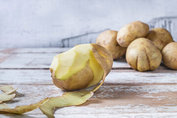 .Potatoes are peeled on wooden background.