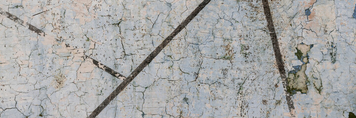 Peeling paint on the wall. Panorama of a concrete wall with old cracked flaking paint. Weathered rough painted surface with patterns of cracks and peeling. Wide panoramic texture for grunge background