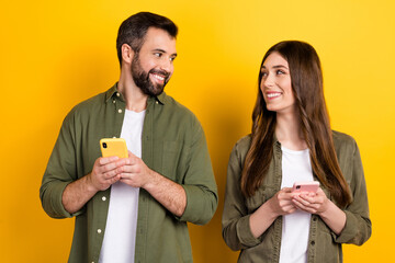 Portrait of attractive cheerful couple using device chatting app 5g post smm isolated over bright...