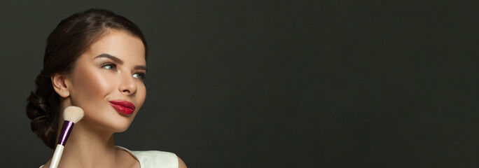 Fototapeta premium Perfect young cheerful woman holding makeup brush on black banner background with copy cpace