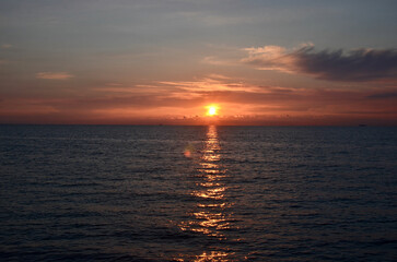 Sunset by the sea scenery, reflections on ripply water surface