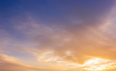 Colorful sunset sky background in the evening with orange sunlight, pink, and blue clouds 