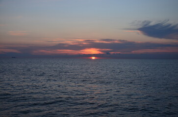 Sunset by the sea scenery, reflections on ripply water surface 