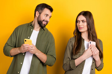 Photo of cheerful funny husband asking wife about sms notifications she hide isolated on yellow color background