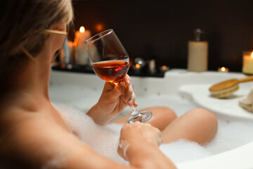 Woman drinking wine while taking bubble bath, closeup. Romantic atmosphere