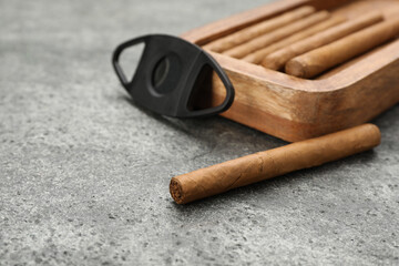 Cigars and guillotine cutter on grey table. Space for text
