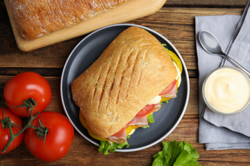 Delicious sandwich with vegetables, ham and mayonnaise served on wooden table, flat lay