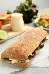 Delicious sandwich with vegetables, ham and mayonnaise on grey table, closeup