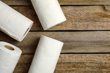Rolls of white paper towels on wooden table, flat lay. Space for text