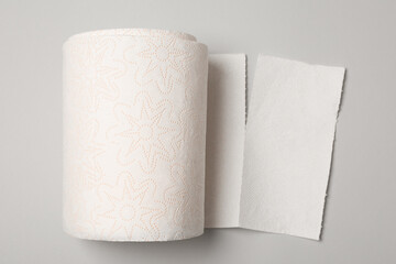Roll of white paper towels on grey background, top view