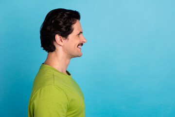 Photo of attractive handsome man wear green t-shirt looking empty space isolated blue color background